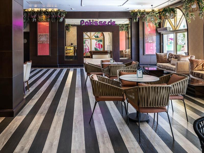 Moderní kavárna s pruhovanou podlahou a pohodlným sezením u velkých oken.