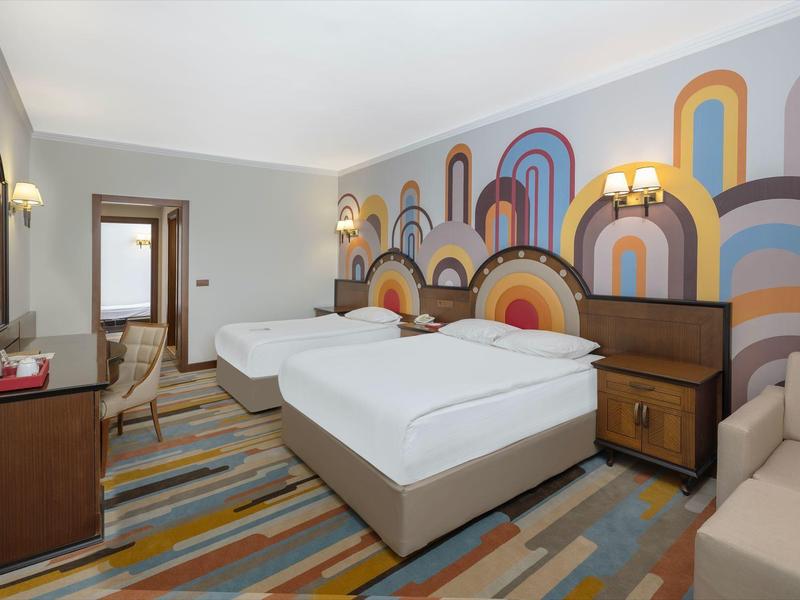 Moderní hotelový pokoj s manželskou postelí, atraktivním barevným nástěnným designem a kobercem.