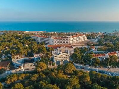 Große Hotelanlage an der Küste, umgeben von Grün und mit Blick auf das blaue Meer.