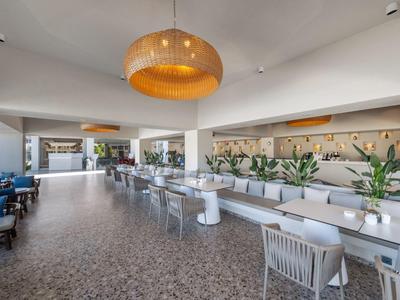 Moderne lichte eetruimte met terrasuitzicht en rijen tafels en stoelen in een hotel.