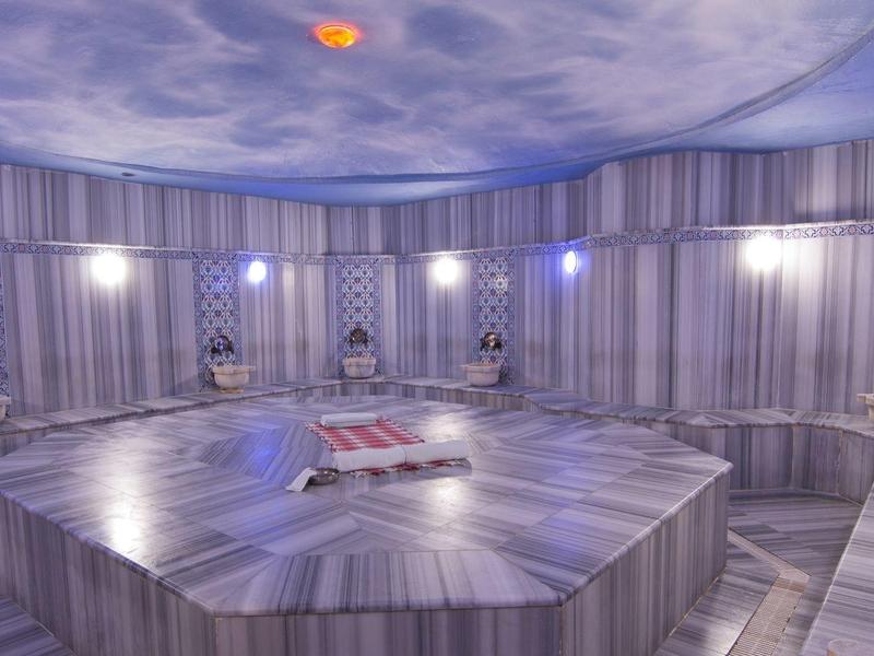 Helder, elegant Turks hammam met stenen zitplaatsen en blauwe verlichting.