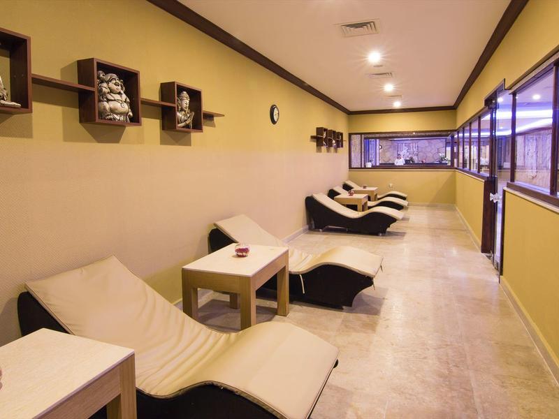 Groot buitengebied met tenten, grasveld en paviljoenen naast een rood rond dak bij vakantieresort.