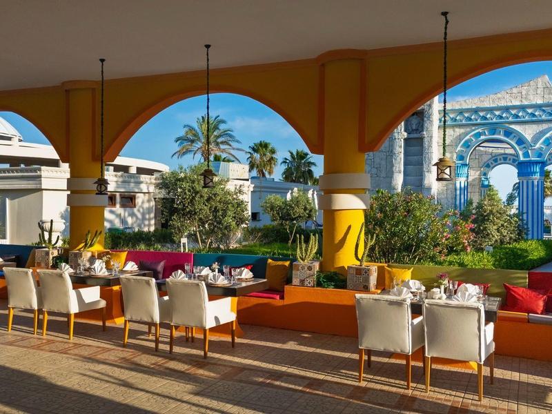 Hotelterras met zitgedeelte en uitzicht op tropische planten en blauwe architectuur