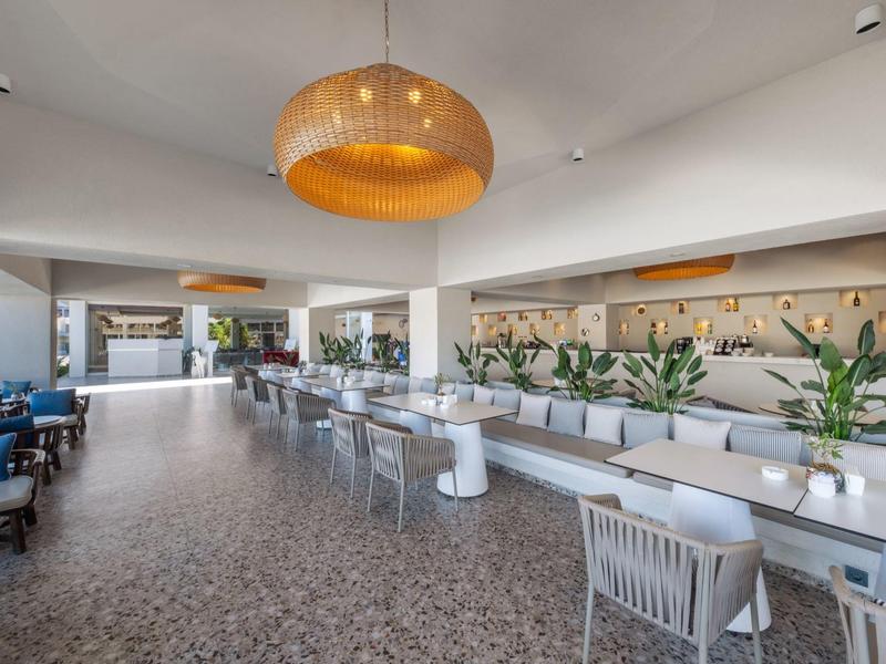 Moderne lichte eetruimte met terrasuitzicht en rijen tafels en stoelen in een hotel.