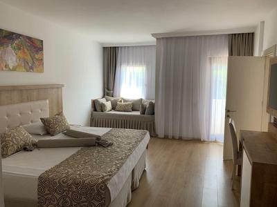 Camera d'hotel accogliente con letti matrimoniali, seduta alla finestra, tende morbide e illuminazione calda.