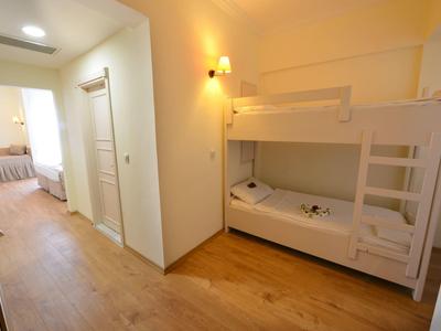 Corridoio con letti a castello in legno e porta che conduce a una camera da letto con letto matrimoniale.