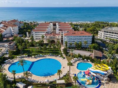 Vista aérea de un hotel con varias piscinas, toboganes de agua y vista al mar al fondo.