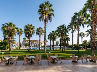 Area pranzo all'aperto con palme e vista mare sotto un cielo soleggiato.