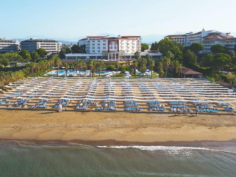 Spiaggia con file di lettini e ombrelloni vicino a un hotel sul mare.