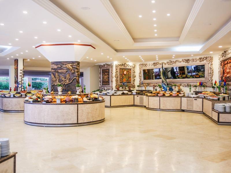 Ampia zona buffet con esposizioni di cibo e luci luminose sul soffitto in una sala da pranzo d'hotel.