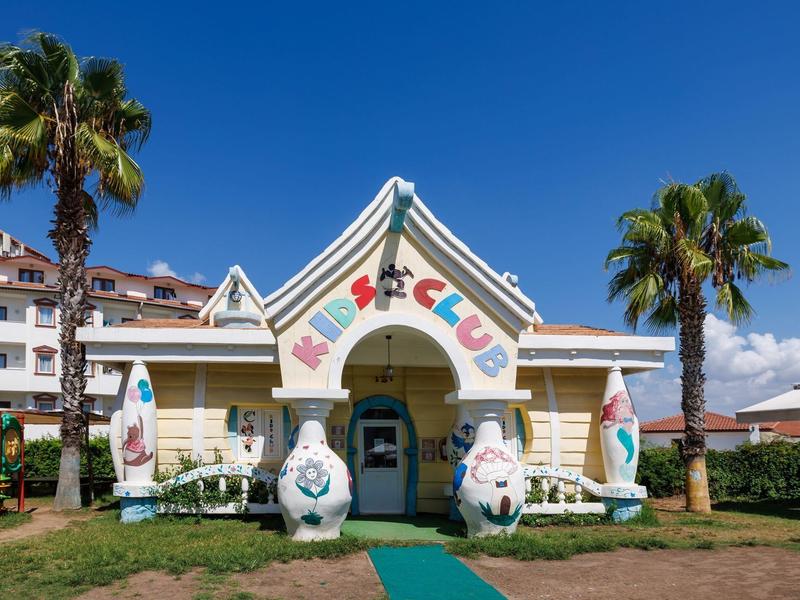 Ingresso colorato di un villaggio vacanze pet-friendly con grandi figure di animali in una giornata soleggiata.