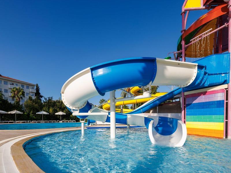 Scivolo d'acqua curvo blu e bianco sopra una piscina in un parco acquatico colorato in una giornata di sole.