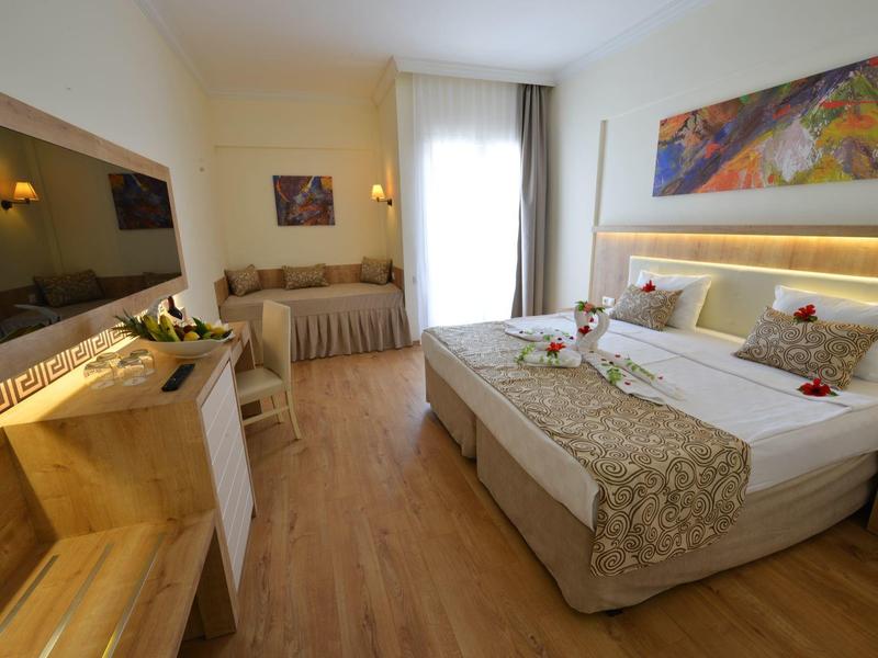 Area giochi acquatica colorata con scivoli accanto a una grande piscina sotto un cielo sereno.