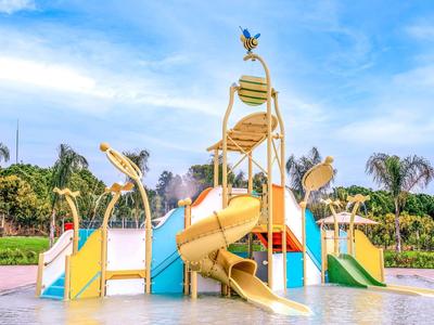 Area giochi acquatica colorata con scivoli e ombrelloni sotto un cielo sereno.