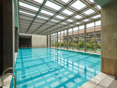 Piscina coperta con tetto in vetro e grandi finestre con vista sul giardino.