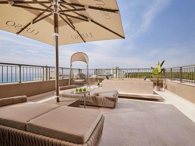 Terrazza sul tetto moderna con lettini, ombrellone e vista sul mare.