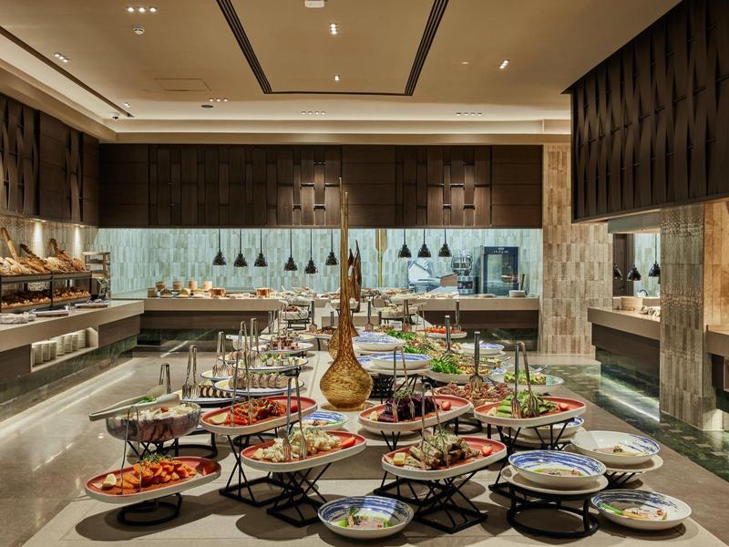 Area buffet dell'hotel con piatti colorati disposti e illuminazione moderna.