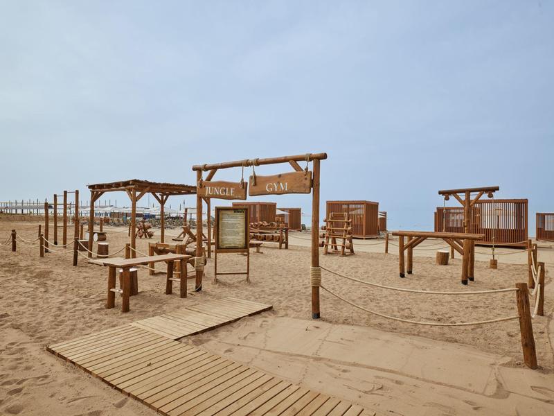 Paesaggio di spiaggia vuoto con pergolati in legno e sentieri sotto un cielo nuvoloso