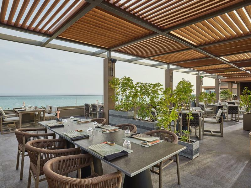 Terrazza coperta con aree salotto e vista mare in un ristorante di hotel.