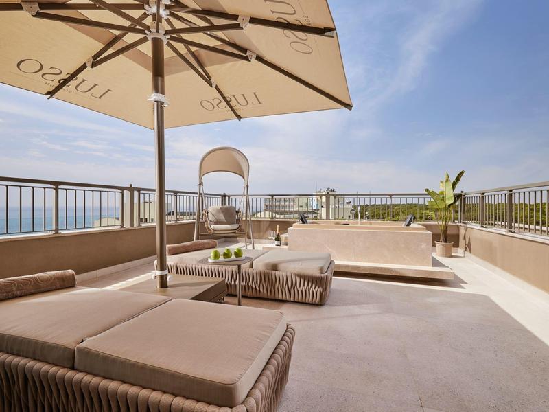 Terrazza sul tetto moderna con lettini, ombrellone e vista sul mare.