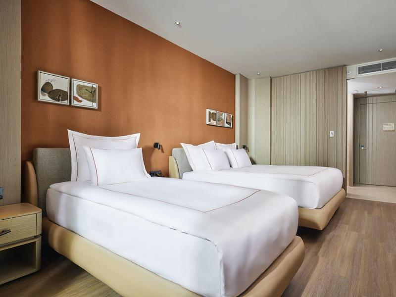 Camera d'hotel moderna con due letti singoli, parete in legno e pavimento in legno