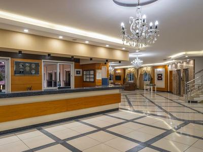 Große Hotellobby mit Empfangstresen, Sitzbereich und Treppe zur oberen Etage.