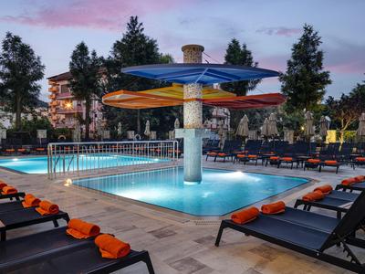 Beleuchteter Hotelpool am Abend mit Liegestühlen und Handtüchern.
