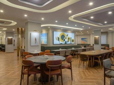 Hell eingerichteter Hotelrestaurantbereich mit Tischen und Stühlen auf Holzboden.