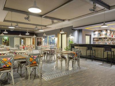 Moderner Hotel-Lobbybereich mit Bar, Stühlen und Tischen in warmem Licht.