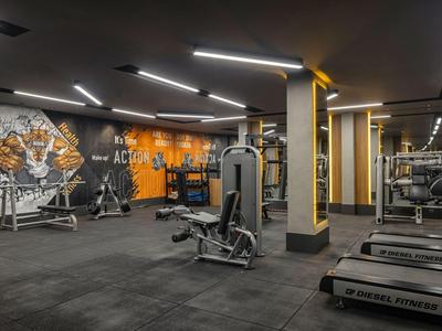 Moderne Fitnessstudio mit Geräten in neutralen Farben und indirekter Beleuchtung.