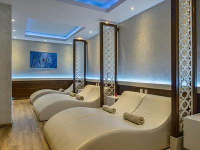 Moderner Wellnessraum mit stilvollen Liegen und großem Aquarium an der Wand.