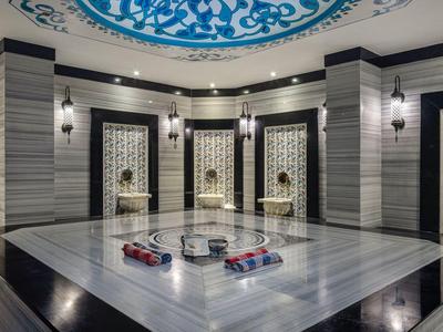 Luxuriöses Spa mit Marmorbecken, geschwungenen Deckenornamenten und weicher Beleuchtung.