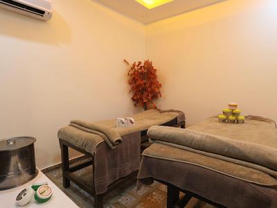 Salle de bien-être chaleureuse et confortable avec deux tables de massage et un éclairage relaxant.