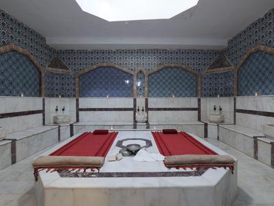 Hammam turc traditionnel avec des bancs en marbre et des murs carrelés bleus.