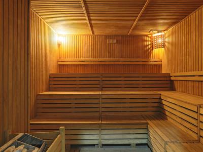 Sauna en bois traditionnel avec plusieurs niveaux d'assise et éclairage chaleureux.