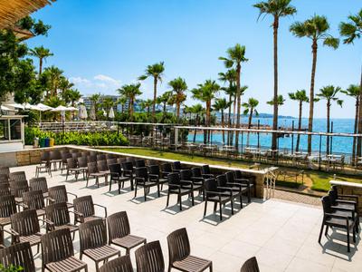 Uitzicht op opgestelde rijen stoelen naast palmbomen met zeezicht bij een hotel.