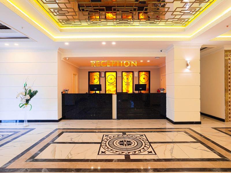 Elegantní hotelová recepce s mramorovou podlahou a teple osvětleným stropem.
