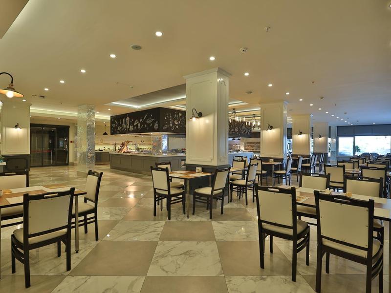 Prostorná, moderní hotelová jídelna s mnoha stoly a židlemi na mramorové podlaze.