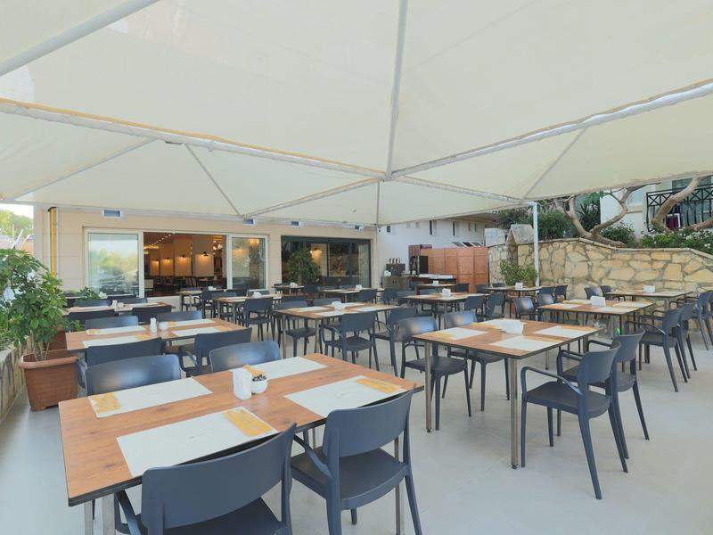 Venkovní restaurace s stoly a židlemi pod velkým slunečníkem