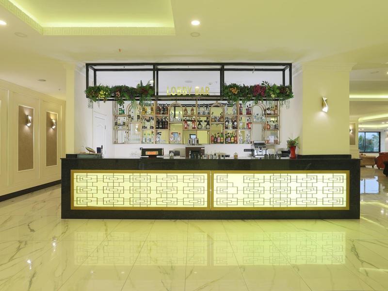 Moderní hotelový bar s osvětleným pultem a policemi s nápoji v pozadí.