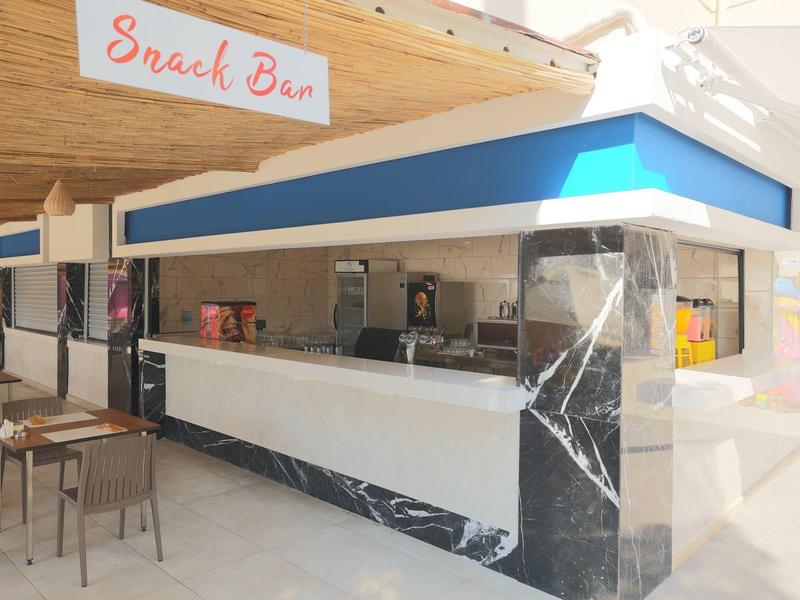 Moderní snack bar s pultem, kávovarem a sezením uvnitř.
