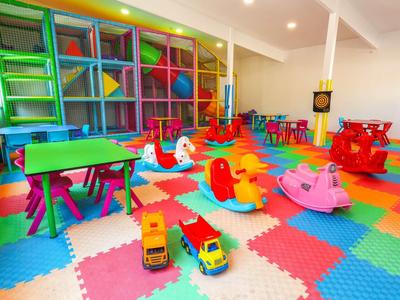 Barevná herna pro děti s měkkou podlahou a různými hračkami a stoly.