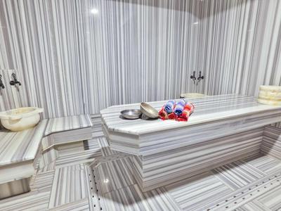 Moderní turecké hammam s vyhřívaným mramorovým masážním stolem a nástěnnými umyvadly.