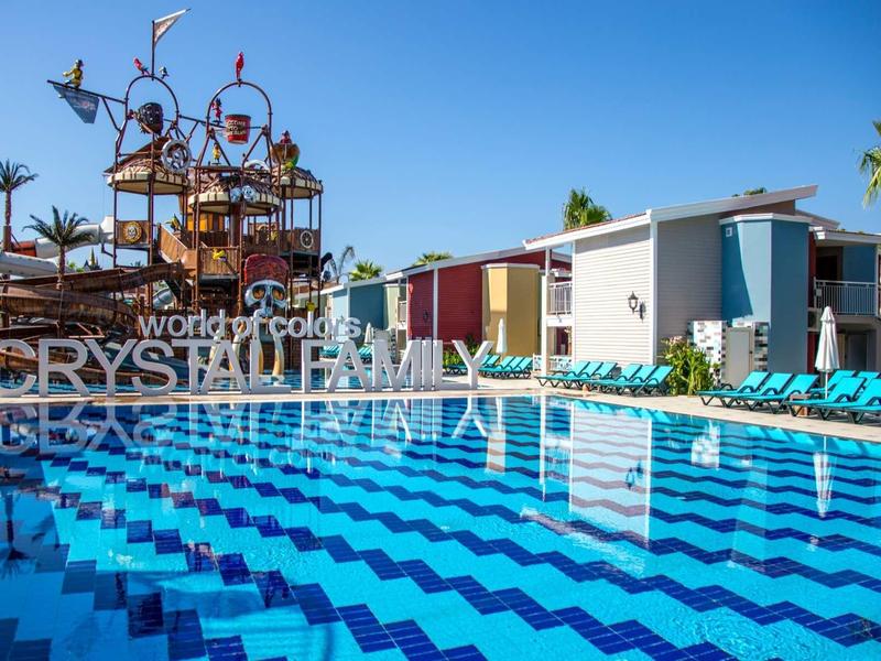 Čistý modrý bazén s lehátky vedle barevné herní věže v hotelovém resortu.