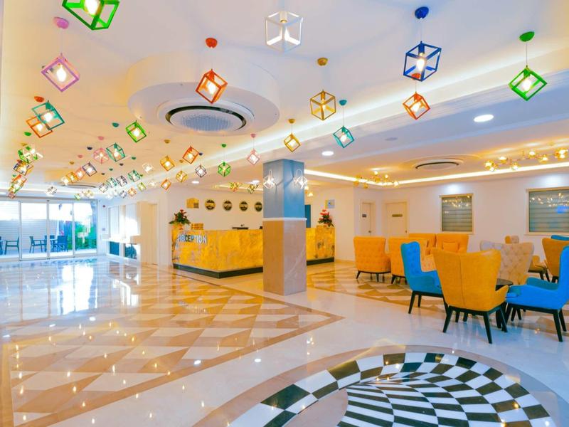 Světlá moderní hotelová hala s barevnými světly a pohodlnými žlutými a modrými židlemi.