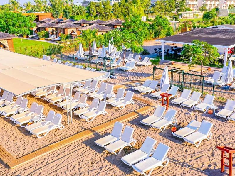 Slunná plážová oblast s lehátky a slunečníky na písku před hotely