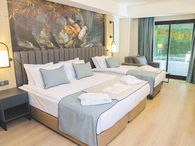 Helles Hotelzimmer mit zwei Doppelbetten, blaugrauer Bettwäsche, Nachttischen und großem Wandbild.