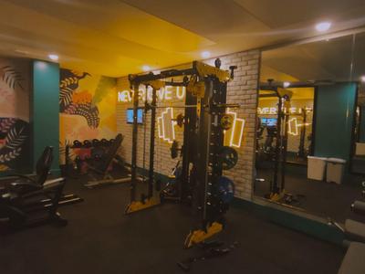 Fitnessraum mit bunten Wänden, Trainingsgeräten, Spiegeln und weichem Bodenbelag.