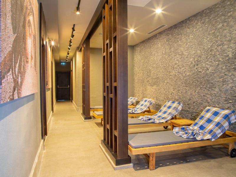Comfortable loungers with pillows along a wall in a hotel corridor.