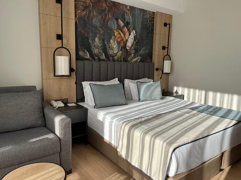 Modern hotel room with double bed, seating area, and decorative wall art.